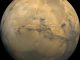 Der Mars. In der Bildmitte erkennt man das größte Canyonsystem des Sonnensystems, Valles Marineris. Die dunklen Flecken links sind die Vulkane Ascraeus Mons, Pavonis Mons und Arsia Mons. Vulkanische Aktivität könnte in der Frühzeit des Planeten genug Methan freigesetzt haben, um wärmere Bedingungen zu schaffen, die flüssiges Wasser auf der Oberfläche ermöglichten. (Jody Swann / Tammy Becker / Alfred McEwen / USGS / NASA)