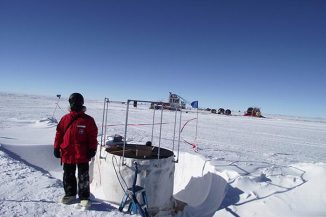 Der Physiker Bakhtiyar Ruzybayev von der University of Delaware neben einem IceTop-Detektor für kosmische Strahlen am Südpol. (University of Delaware)