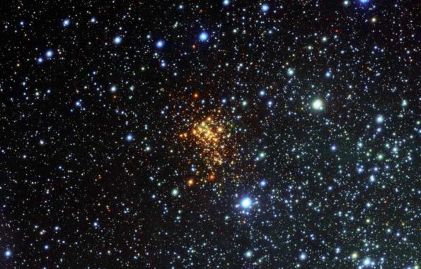 Das neue VST-Bild des Sternhaufens Westerlund 1. Die Sterne in dem Sternhaufen erscheinen rot aufgrund von Staub, der ihr blaues Licht blockiert. Die blauen Sterne sind Vordergrundobjekte und gehören nicht zu dem Sternhaufen. Der Stern W26 befindet sich oben links in dem Sternhaufen und ist von einem grünen Leuchten umgeben. (ESO / VPHAS+ Survey / N. Wright)