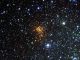 Das neue VST-Bild des Sternhaufens Westerlund 1. Die Sterne in dem Sternhaufen erscheinen rot aufgrund von Staub, der ihr blaues Licht blockiert. Die blauen Sterne sind Vordergrundobjekte und gehören nicht zu dem Sternhaufen. Der Stern W26 befindet sich oben links in dem Sternhaufen und ist von einem grünen Leuchten umgeben. (ESO / VPHAS+ Survey / N. Wright)