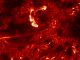Diese IRIS-Aufnahme zeigt Emissionen von heißem Plasma in der Übergangsregion zwischen der Sonnenoberfläche und der äußeren Korona. Die helle, C-förmige Struktur oberhalb der Bildmitte stellt eine Aufhellung in den Ausgangspunkten heißer koronaler Bögen dar, verursacht durch hochenergetische Elektronen. Die Elektronen werden von Nanoflares beschleunigt. Die Auflösung liegt bei 120 Kilometern pro Pixel. (NASA / IRIS)