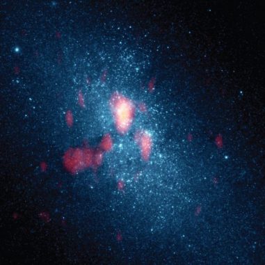 Optische Hubble-Aufnahme der Zwerggalaxie NGC 5253, kombiniert mit Beobachtungen des molekularen Gases mit dem Submillimeter Array (rot). Die helle Zentralregion scheint Sterne mit einer zehnfach höheren Rate zu produzieren als unsere Milchstraßen-Galaxie, möglicherweise aufgrund des von der linken Seite einfallenden Gases. (Nature; NASA HST; SMA)