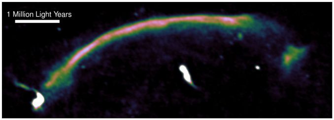 Radiodaten heben die Schockwelle innerhalb des Sausage-Galaxienhaufens hervor. Sie ist als der helle Bogen erkennbar, der von unten links nach oben rechts verläuft. Die Schockwelle entstand vor einer Milliarde Jahren, als die beiden ursprünglichen Galaxienhaufen kollidierten, und sie bewegt sich mit etwa neun Millionen Kilometern pro Stunde. (Andra Stroe)