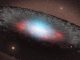 Diese Illustration zeigt ein supermassives Schwarzes Loch im Zentrum einer Galaxie. Die bläulichen Farbtöne repräsentieren Strahlung, die von der Materie in der direkten Umgebung des Schwarzen Lochs emittiert wird. Die graue Struktur, die das Schwarze Loch umgibt, besteht aus Gas und Staub. (NASA / JPL-Caltech)