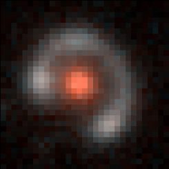 Auf diesem Farbkompositbild ist die als Gravitationslinse agierende Galaxie rot markiert. Der Einsteinring (bläulich) ist das verzerrte Abbild einer fernen Galaxie. (Bettinelli et al., DECam (Blanco 4-m telescope at CTIO))