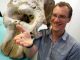Dr. Alistair Evans mit einem Elefantenschädel im Hintergrund und dem Schädel einer Maus in der Hand (Monash University)
