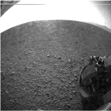 Dies ist eines der ersten Bilder, die der Mars-Rover Curiosity zurückgeschickt hat. Es wurde mit einer Fischaugen-Linse im linken "Auge" einer Stereo-Kamera gemacht. Der helle Bogen ist ein Sättigungseffekt durch die Helligkeit der Sonne. (NASA / JPL-Caltech)