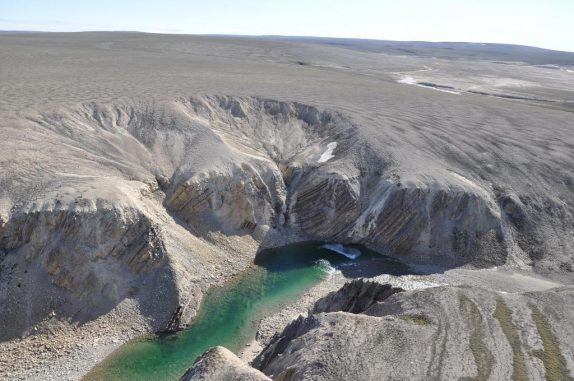 Luftbild des Gebietes. Neben dem Fluss George sind steil abfallende Sedimentschichten erkennbar. Diese deformierten Gesteinsbetten repräsentieren die zentrale Erhebung, die durch die Rückfederung des Gesteins nach dem Einschlag entsteht. (Photo by Brian Pratt) Luftbild des Gebietes. Neben dem Fluss George sind steil abfallende Sedimentschichten erkennbar. Diese deformierten Gesteinsbetten repräsentieren die zentrale Erhebung, die durch die Rückfederung des Gesteins nach dem Einschlag entsteht. (Photo by Brian Pratt)
