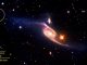 Die Balkenspiralgalaxie NGC 6872 ist die größte bekannte Spiralgalaxie. Am Ende des nordwestlichen Spiralarms ist im ultravioletten Spektrum ein Zwerggalaxie-Kandidat erkennbar (Kreis). (NASA / Goddard Space Flight Center / ESO / JPL-Caltech / DSS)
