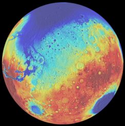 Dieses Falschfarbenbild des Mars zeigt Höhenunterschiede auf seiner Oberfläche. Blaue Gebiete markieren tiefe Regionen, rote kennzeichnen höher gelegene Areale. Das Borealis-Becken befindet sich oben, das Hellas-Becken unten rechts und das Argyre-Becken unten links. (Credits: University of Arizona / LPL / Southwest Research Institute)