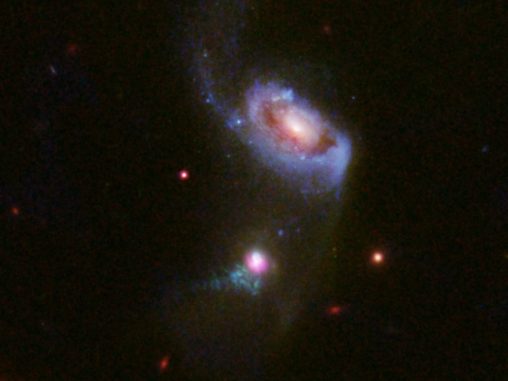 Hubble-Aufnahme der Galaxie SDSS J1354+1327 (unten) mit zwei abgestoßenen Gasblasen. (Credits: NASA, ESA, and J. Comerford (University of Colorado-Boulder))