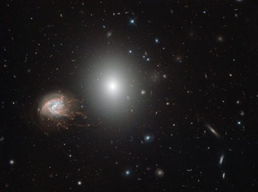 Die beiden Galaxien NGC 4680 (Mitte) und NGC 4858 (links), aufgenommen vom Weltraumteleskop Hubble. (Credits: ESA / Hubble & NASA)