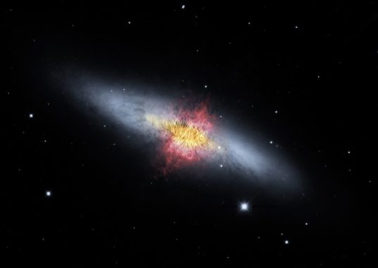 Kompositbild der Zigarrengalaxie M82. Das von SOFIA registrierte Magnetfeld (schwarze Linien) scheint den bipolaren Abströmungen (rot) zu folgen. Das Bild kombiniert sichtbares Licht (grau) und registriertes Wasserstoffgas (rot) des Kitt Peak Observatory mit nah- und mittelinfrarotem Sternlicht und Staub (gelb) von SOFIA und dem Weltraumteleskop Spitzer. (Credits: NASA / SOFIA / E. Lopez-Rodriguez; NASA / Spitzer / J. Moustakas et al.) Kompositbild der Zigarrengalaxie M82. Das von SOFIA registrierte Magnetfeld (schwarze Linien) scheint den bipolaren Abströmungen (rot) zu folgen. Das Bild kombiniert sichtbares Licht (grau) und registriertes Wasserstoffgas (rot) des Kitt Peak Observatory mit nah- und mittelinfrarotem Sternlicht und Staub (gelb) von SOFIA und dem Weltraumteleskop Spitzer. (Credits: NASA / SOFIA / E. Lopez-Rodriguez; NASA / Spitzer / J. Moustakas et al.)