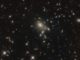 Die dem Gravitationslinseneffekt unterliegende Galaxie PLCK G045.1+61.1 ist in Form mehrerer rötlicher Punkte nahe der Bildmitte erkennbar. (Credit: ESA / Hubble & NASA, B. Frye)