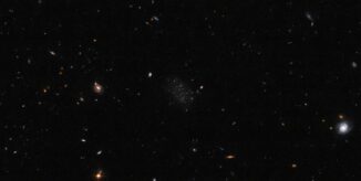 Ein schwarzes, größtenteils leeres Feld mit zerstreuten Sternen und Galaxien. In der Mitte liegt eine kleine, irreguläre Zwerggalaxie namens Donatiello II. (Credit: ESA /Hubble & NASA, B. Mutlu-Pakdil; Acknowledgement: G. Donatiello)